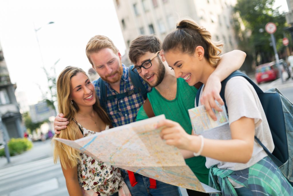 Friends looking at map together on city street.